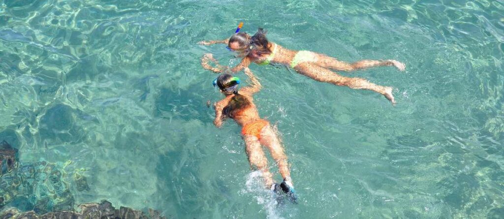 Two girls snorkelling in blue ocean